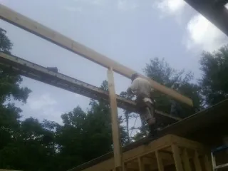 Carpenter setting a ridge beam over a new addition frame — Ice Dam Removal by Roofing Brothers in Centerview