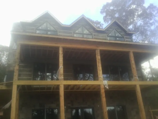 Dormers and porch framing on a large log home under construction — Roof Coating work by our crew in Centerview