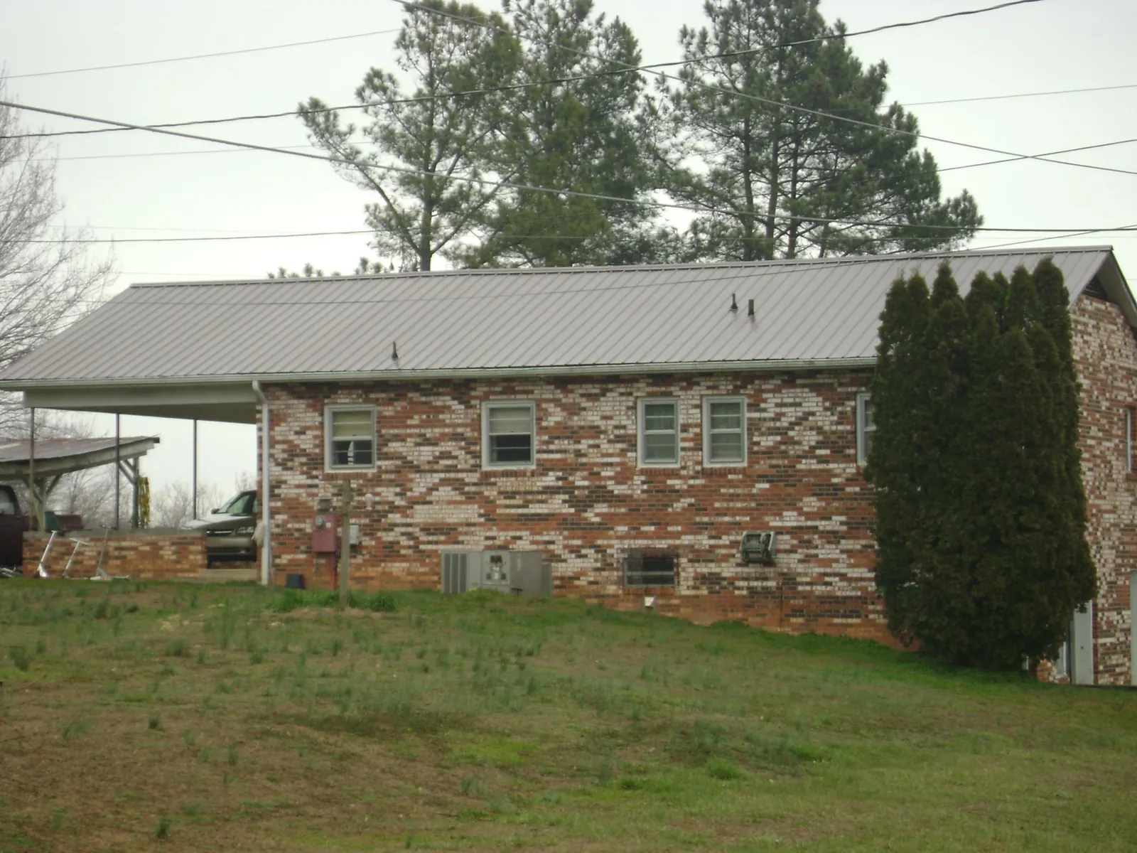 Gray metal roof on a brick split level home with a carport in Centerview