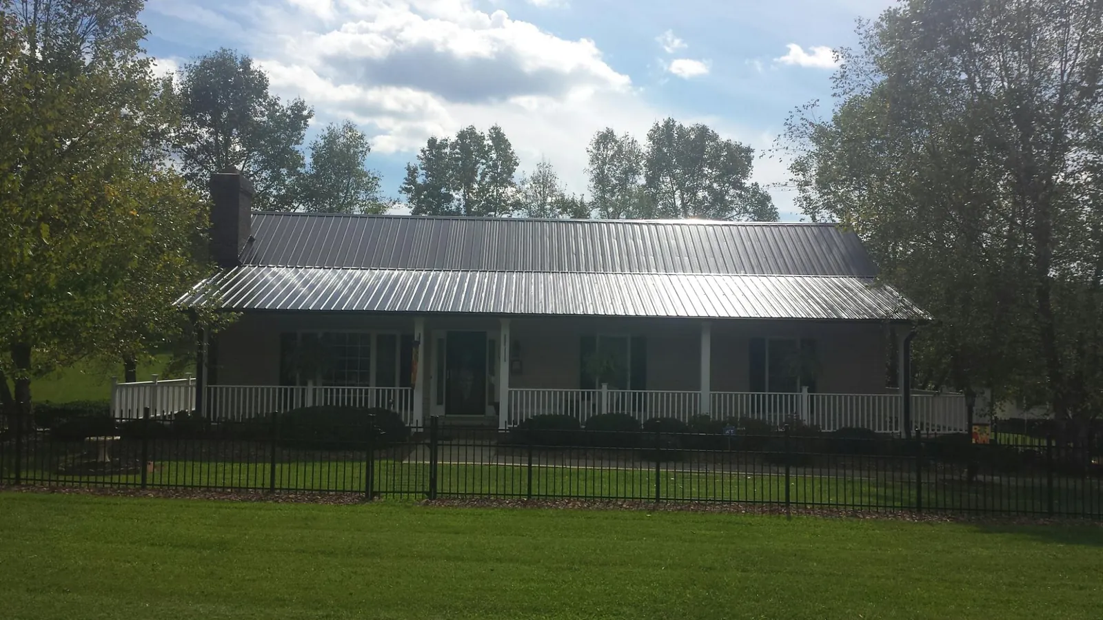Gray metal roof on a brick ranch with a full width front porch — Gutter Guard Installation work by our crew in Centerview